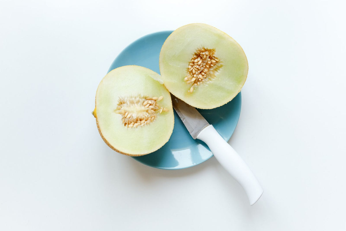 Two honeydew melon halves with pale green flesh and central seeds